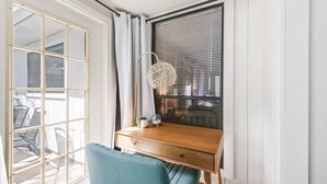 A room with a wooden desk, a blue chair, a lamp, and a window with blinds. - 4BDR+GameRoom+GroupsWelcome+Extd Stay Discounts (Corpus Christi)