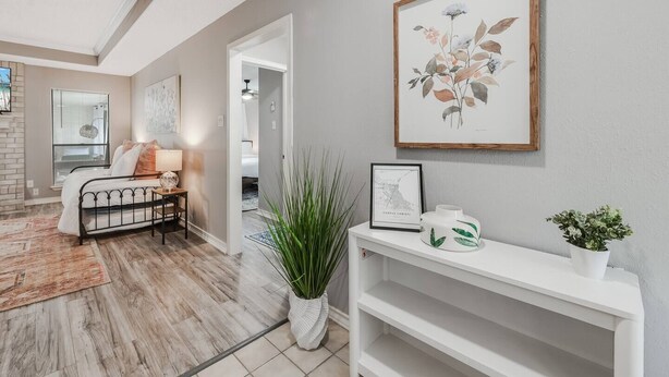 A modern living room with a bed, a white console table, a framed botanical print, and a potted plant. - 4BDR+GameRoom+GroupsWelcome+Extd Stay Discounts (Corpus Christi)