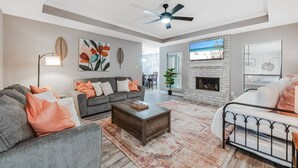 A spacious living room with a gray sofa, a coffee table, and a fireplace. - 4BDR+GameRoom+GroupsWelcome+Extd Stay Discounts (Corpus Christi)