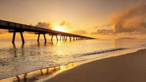 A pier extending into calm waters at sunset.