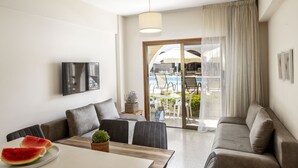 Ein modernes Wohnzimmer mit einer Couch, einem Esstisch und Blick auf einen Außenpool.
