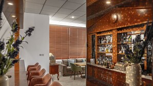Eine Bar mit Holzböden, voll mit Flaschen, eine Sitzecke mit Sofas und Sesseln sowie ein Empfangstresen.