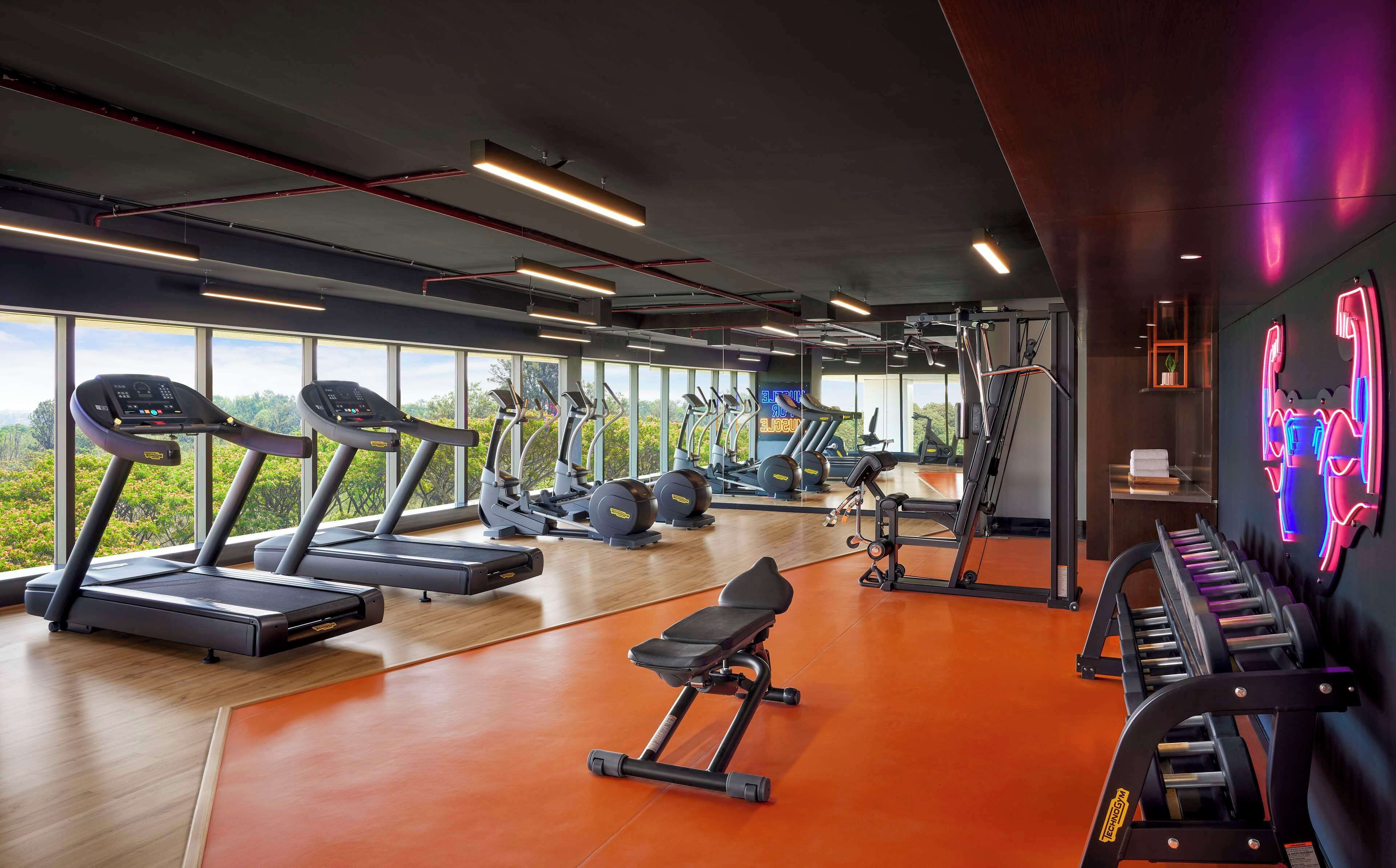 Una palestra con tapis roulant, ellittiche e macchinari per l'allenamento con i pesi.