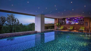 A modern indoor swimming pool with a view of the cityscape at dusk. - Hyatt Centric Hebbal Bengaluru (Bengaluru)
