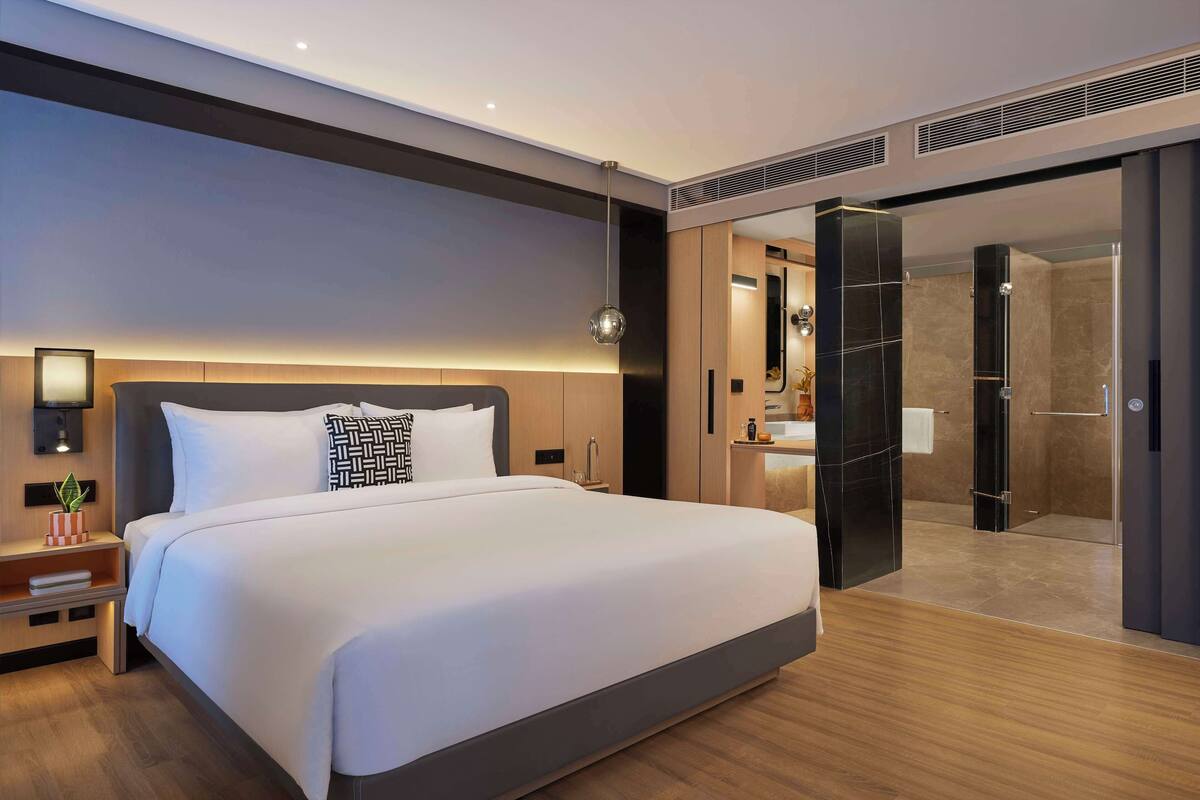 Une chambre d’hôtel moderne avec un grand lit, une table de chevet et un dressing.