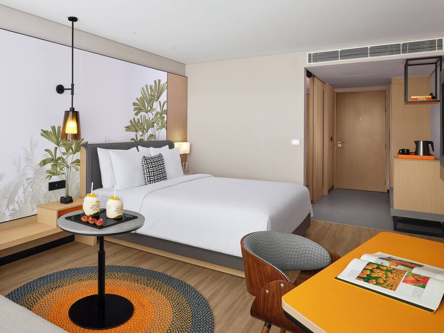 A hotel room with a bed, bedside table, lamp, and a small table with a magazine.
