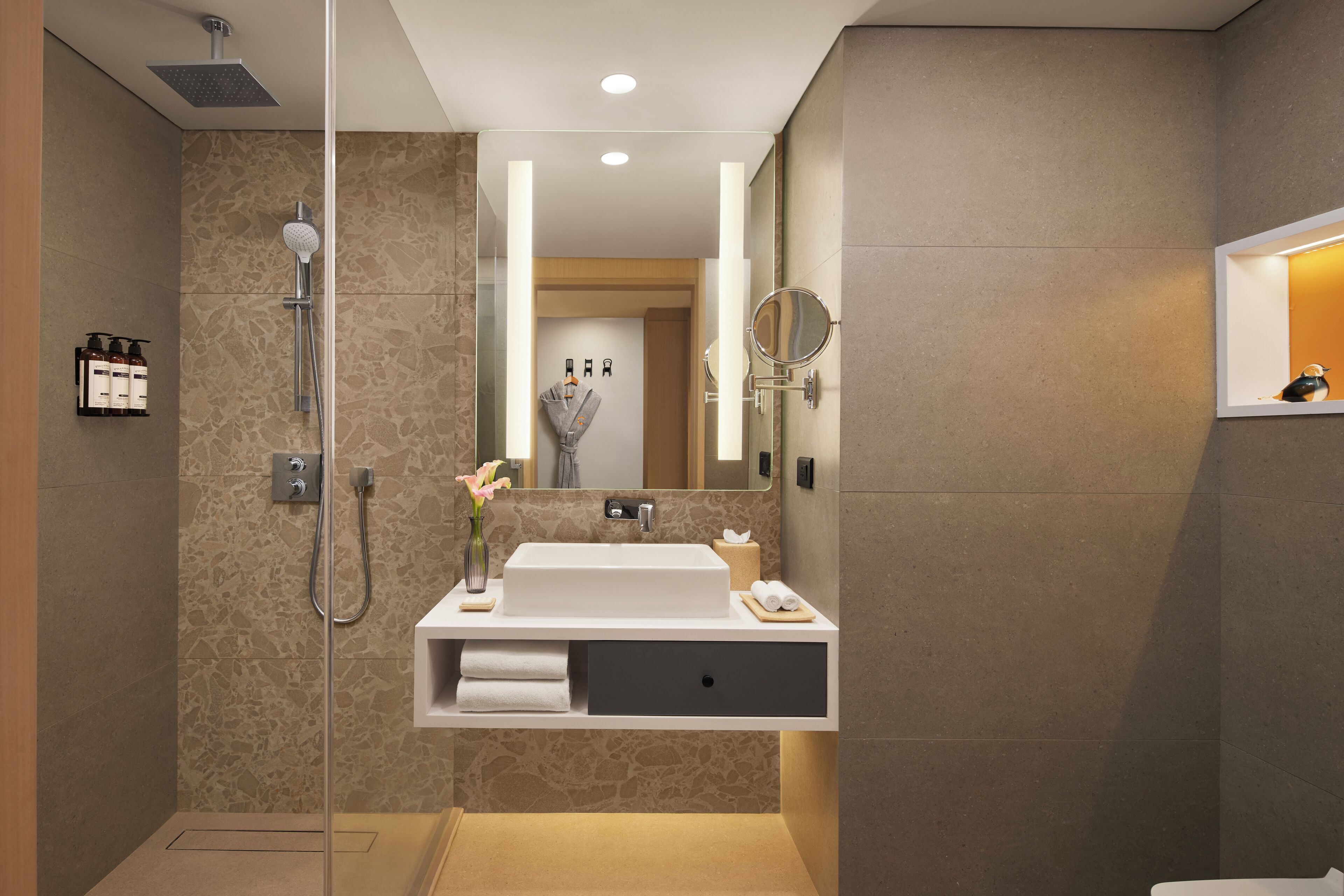 Un baño moderno con ducha de vidrio, lavamanos integrado y un espejo.