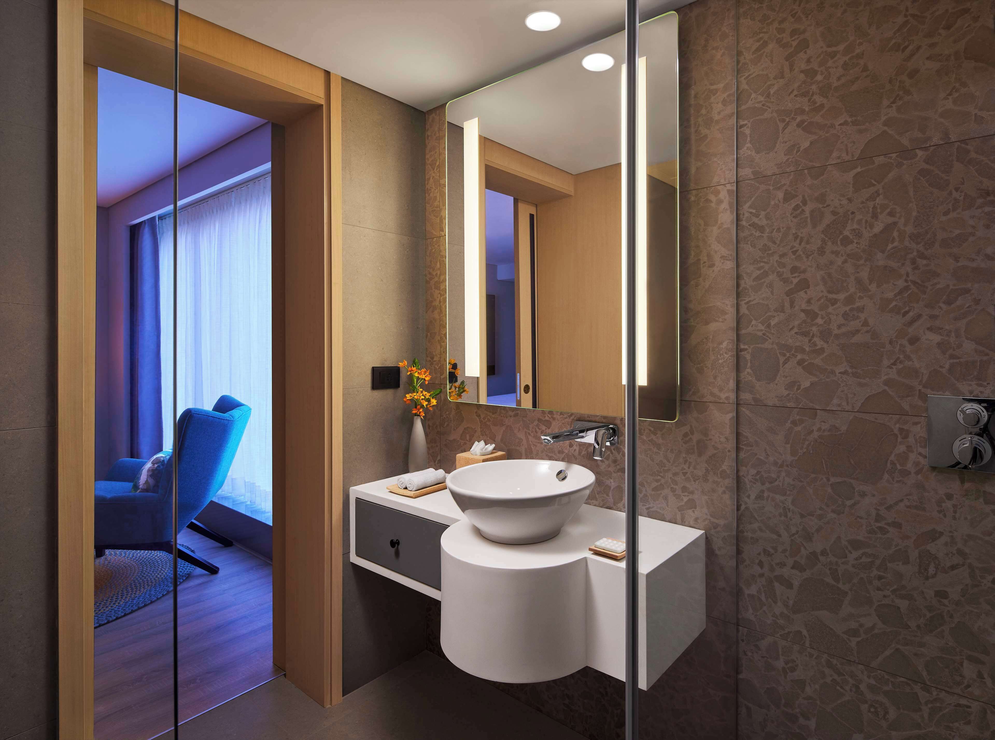 A modern bathroom with a large mirror, a white sink, and a shower area.