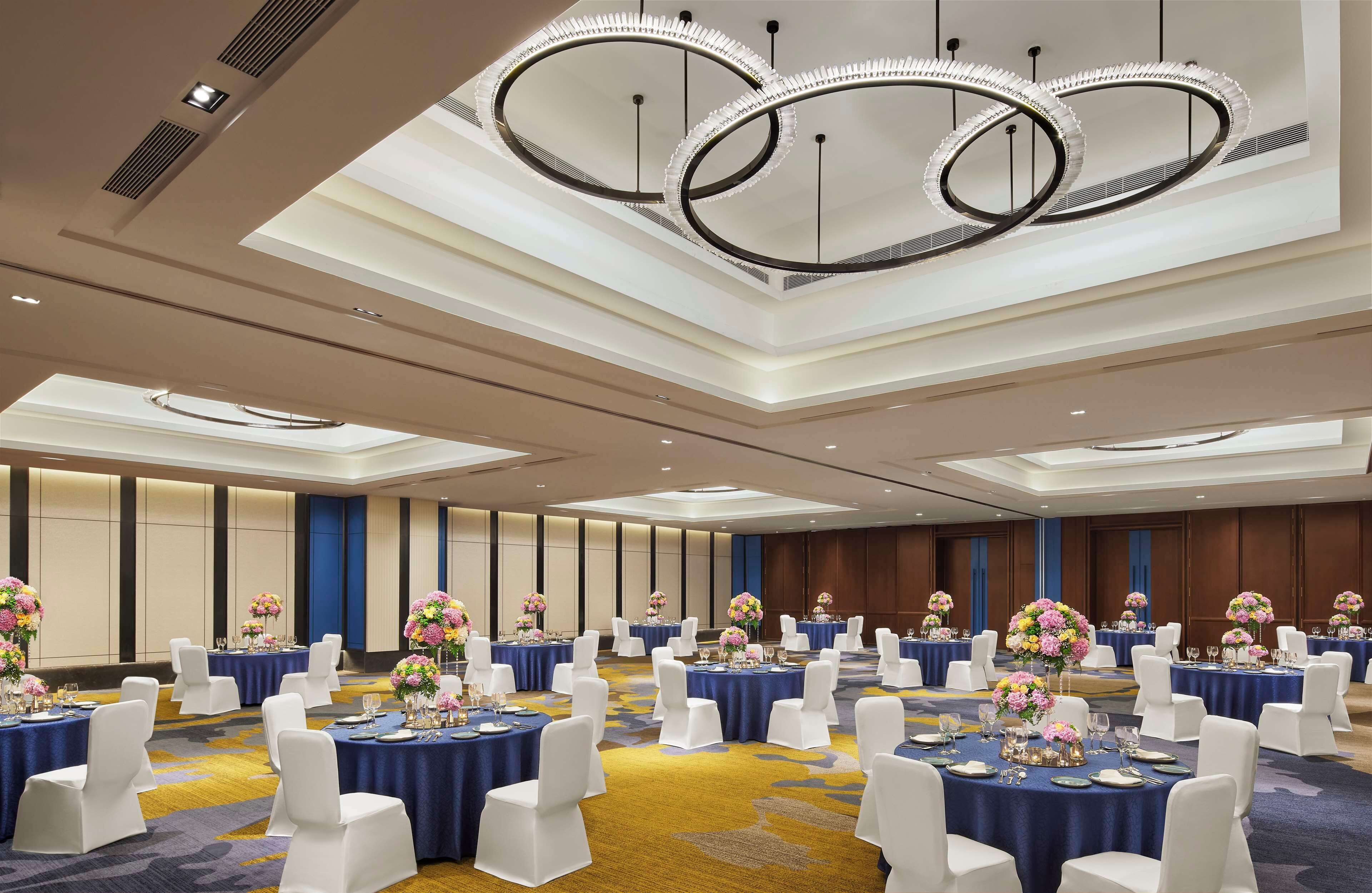A conference room with round tables, white chairs, and floral centerpieces.