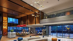 A spacious lobby with a high ceiling, modern furniture, and large windows offering views of the cityscape. - Hyatt Centric Hebbal Bengaluru (Bengaluru)