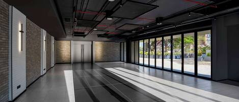A modern hallway with a patterned floor, large windows, and a brick wall.