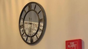 Cozinha com design moderno, destacando uma pia de aço inoxidável, bancada preta e um relógio decorativo com números romanos.