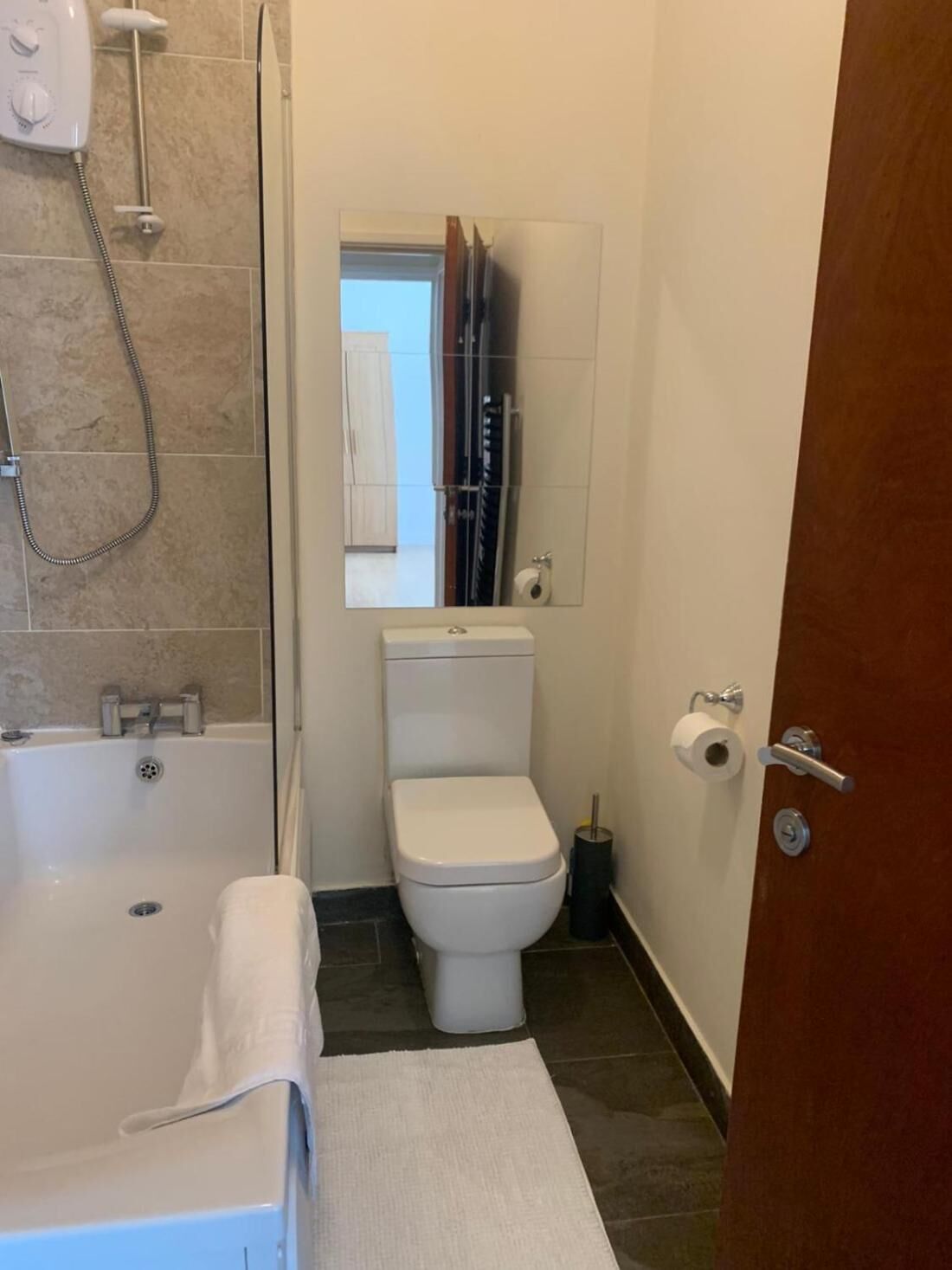 Een kleine badkamer met bad, toilet en douche.