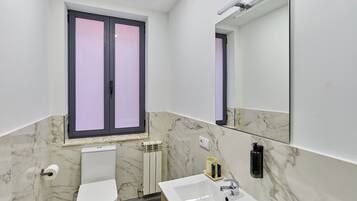 A modern bathroom with a toilet, sink, and a window with frosted glass.