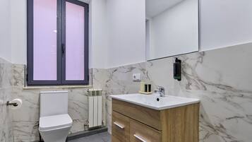 A modern bathroom with a toilet, vanity, and a large mirror.