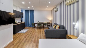 A modern, compact living space with a kitchenette, a dining area, and a seating area with a sofa and a TV. - Apartamentos Margarita by gaiarooms  (Salamanca)