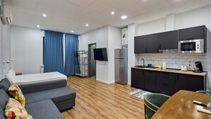 A modern hotel room with a sofa, a dining table, a kitchen area, and a separate entrance. - Apartamentos Margarita by gaiarooms  (Salamanca)
