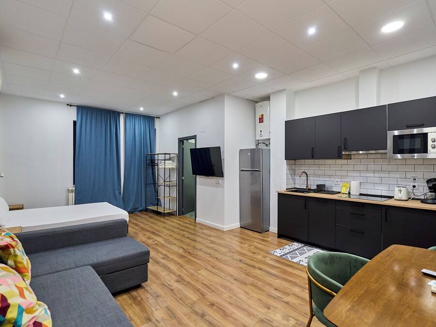 Una habitación de hotel moderna con sofá, mesa de comedor, zona de cocina y entrada independiente.