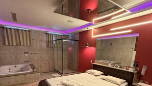 A modern bedroom with a large bed, a separate shower area, and a vanity with a mirror. - Motel Laddak (Gama)