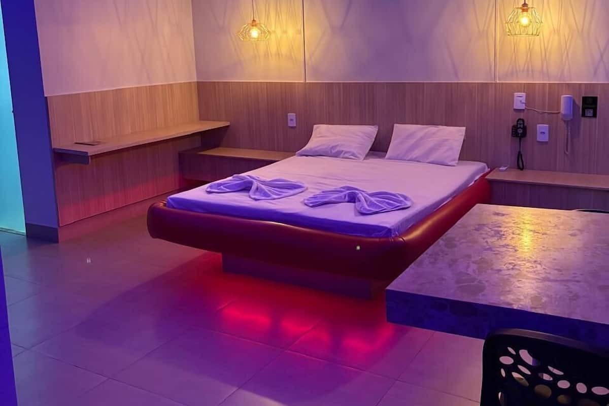 A modern hotel room with a bed, a desk, and a chair.