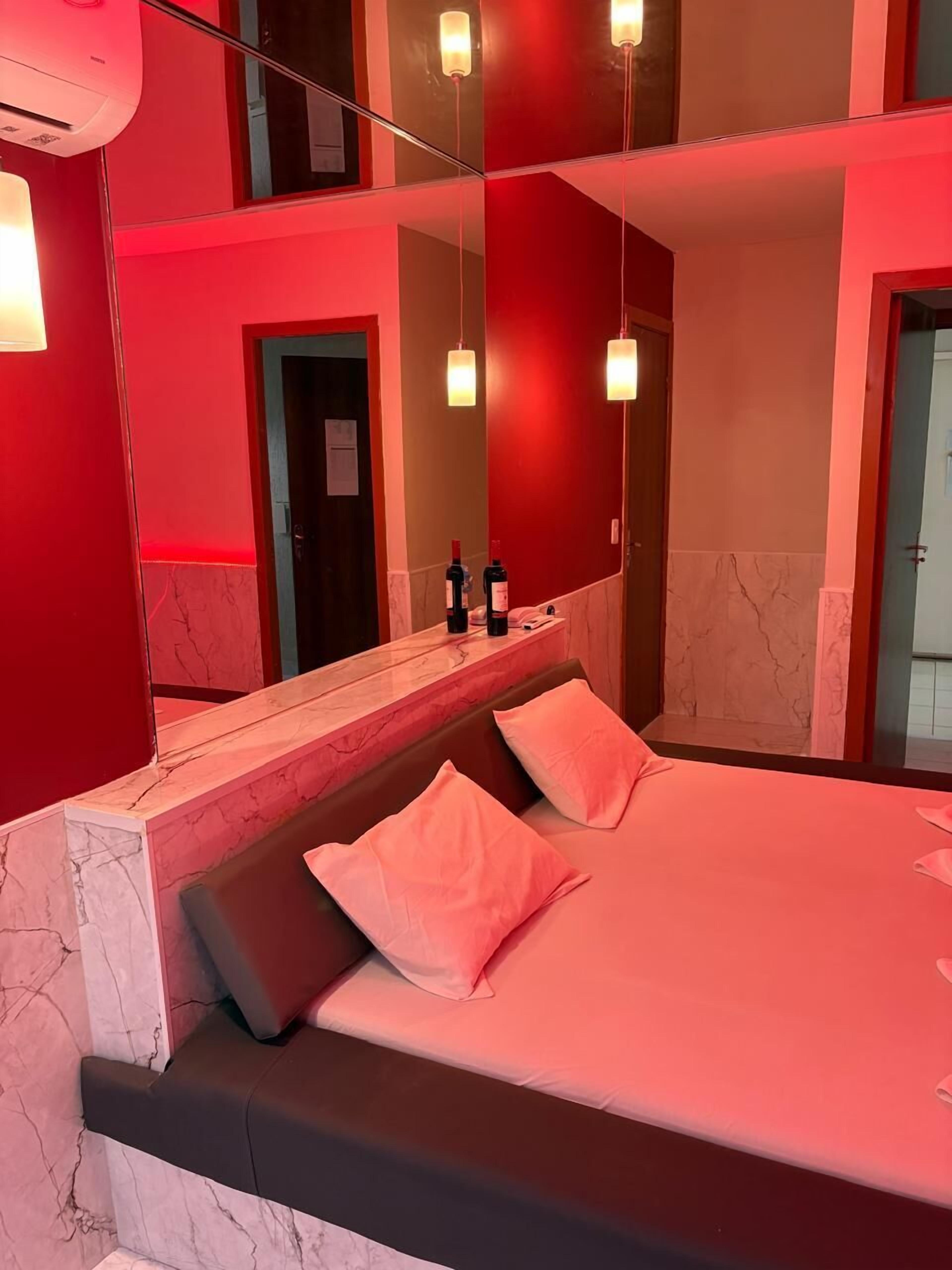 A modern hotel room with a large bed, a marble-topped bedside table, and a large mirror reflecting the room.