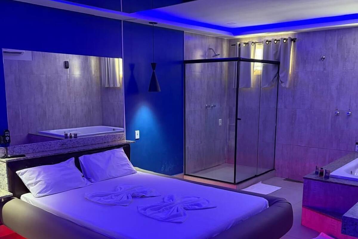A modern bedroom with a large bed, a separate bathroom, and a walk-in closet.