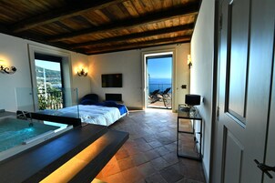 Un dormitorio con una cama grande, una bañera y un balcón con vista al mar.