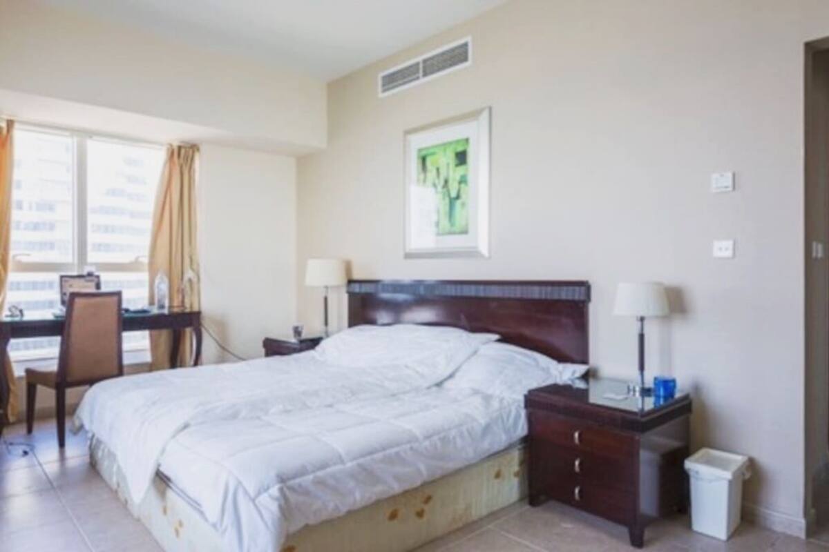 A hotel room with a bed, bedside tables, a desk, and a chair.