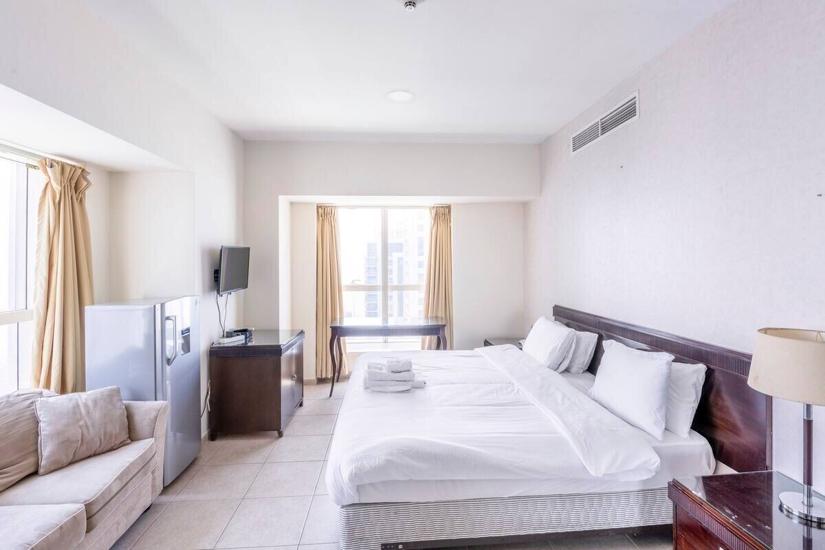 A hotel room with a large bed, a desk, a television, and a sofa.