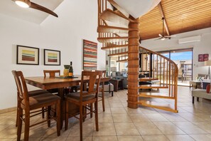 Ein geräumiger Wohnbereich mit einer Holztreppe, einem Esstisch mit Stühlen und einem Sofa.