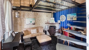 Una sala de estar acogedora con pared de piedra, un sofá, una mesa de centro y una chimenea.
