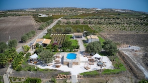 Vista aérea de una propiedad con piscina, mobiliario exterior y viñedo.