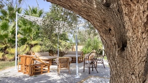 Un área de estar al aire libre con mobiliario de madera y una pérgola.
