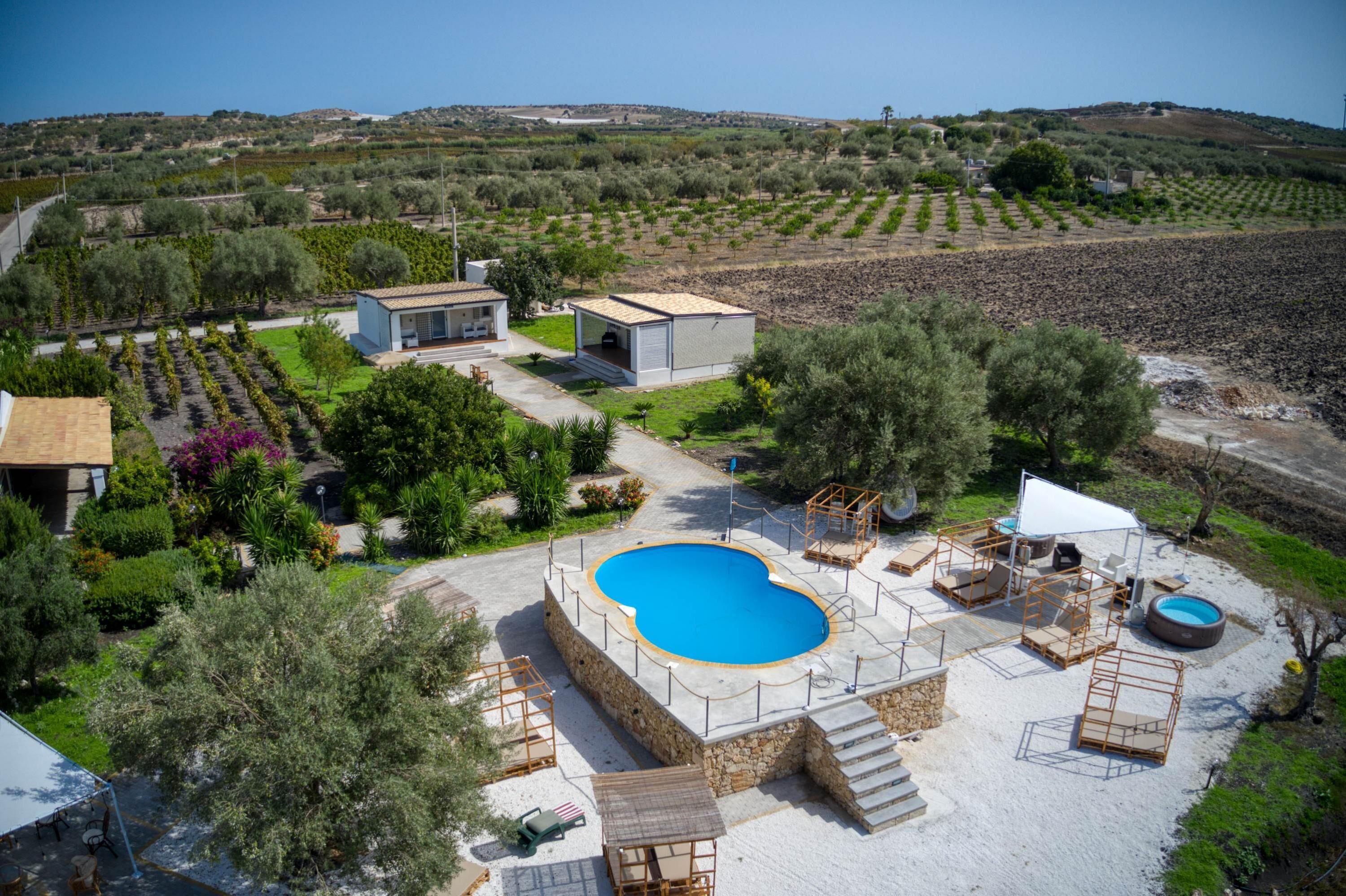 A villa with a swimming pool, outdoor seating, and a garden.