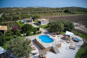 A villa with a swimming pool, outdoor seating, and a garden.
