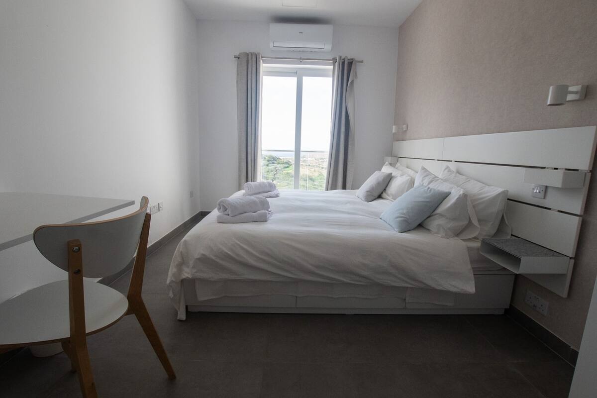 Ein modernes Hotelzimmer mit einem großen Bett, einem Schreibtisch und einem Stuhl.