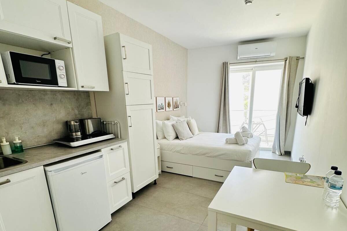 Eine kompakte, moderne Wohnung mit Küchenzeile, Essbereich und Schlafzimmer.