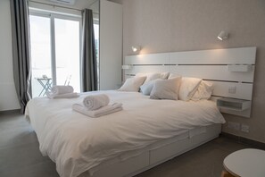 A modern hotel room with a large bed, a bedside table, and a view through a large window. - Gest (Mellieha)