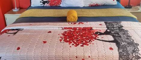 A bed with a tufted headboard, multiple pillows, a blanket, and a decorative tree design on the bedspread.