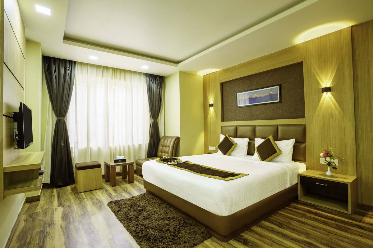 A hotel room with a large bed, a TV, a desk, and a chair.