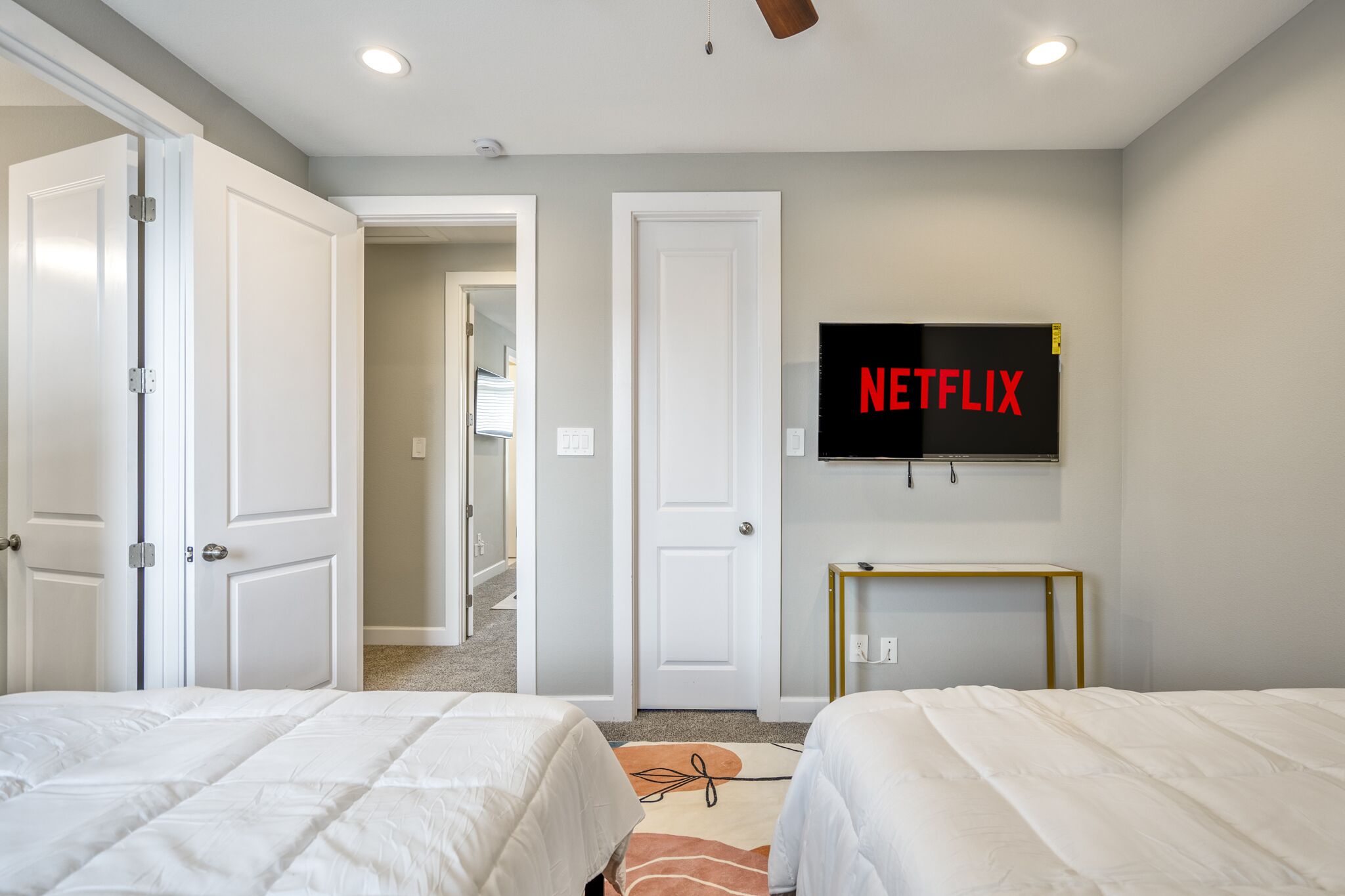 A hotel room with two beds, a TV mounted on the wall, and a door leading to another room.