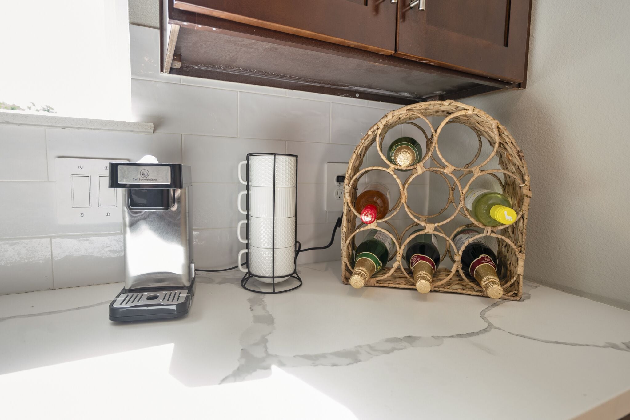 A kitchen counter with a coffee maker, a mug, and a wine rack.