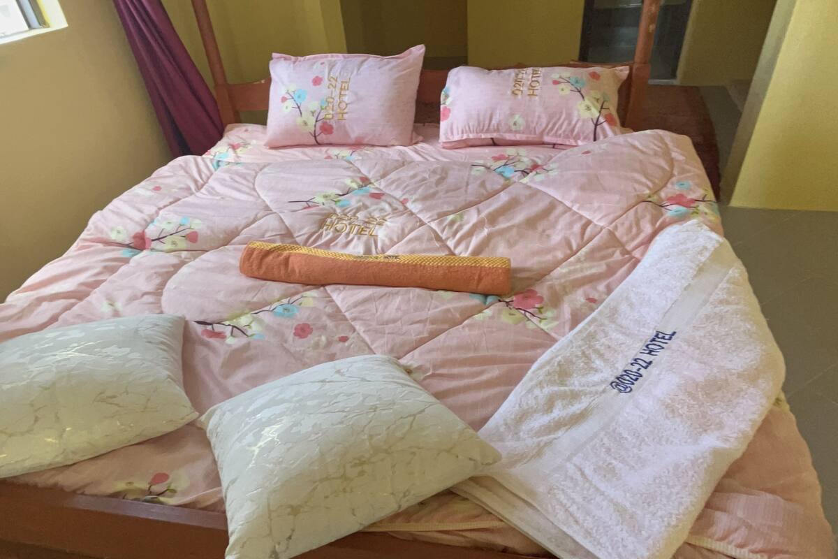 A bed with floral bedding and pillows, a blanket, and a tag reading "Hotel".