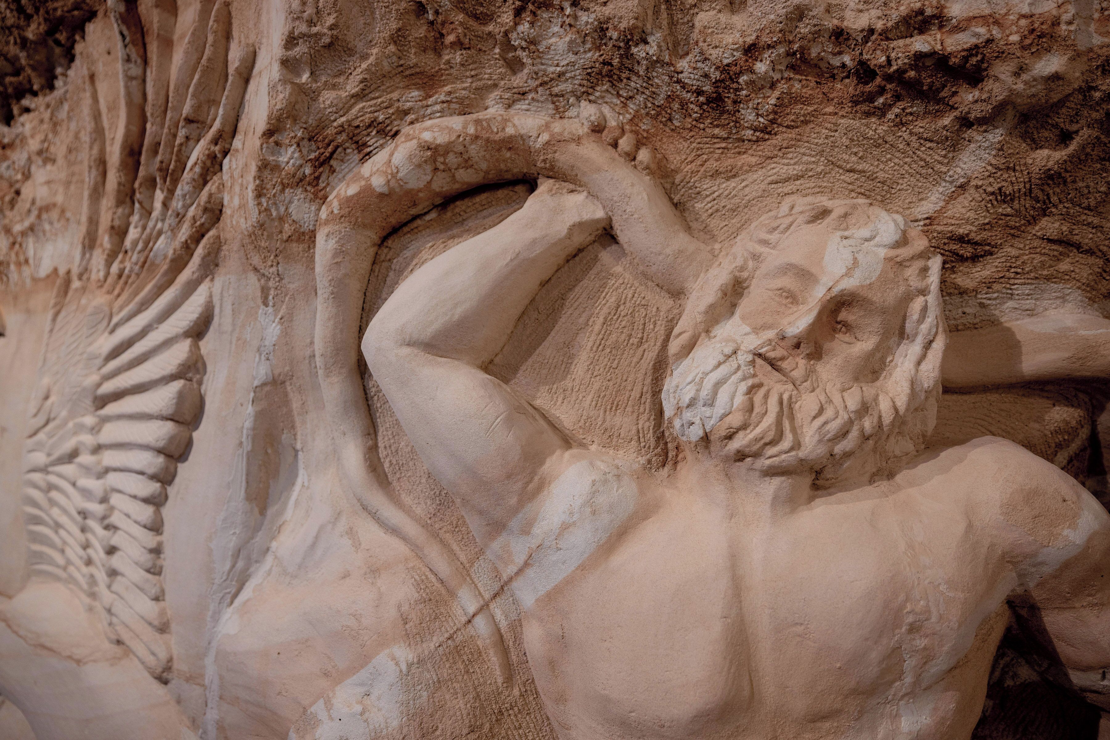 A detailed sculpture of a bearded man with a muscular build, holding his head in a thoughtful pose.