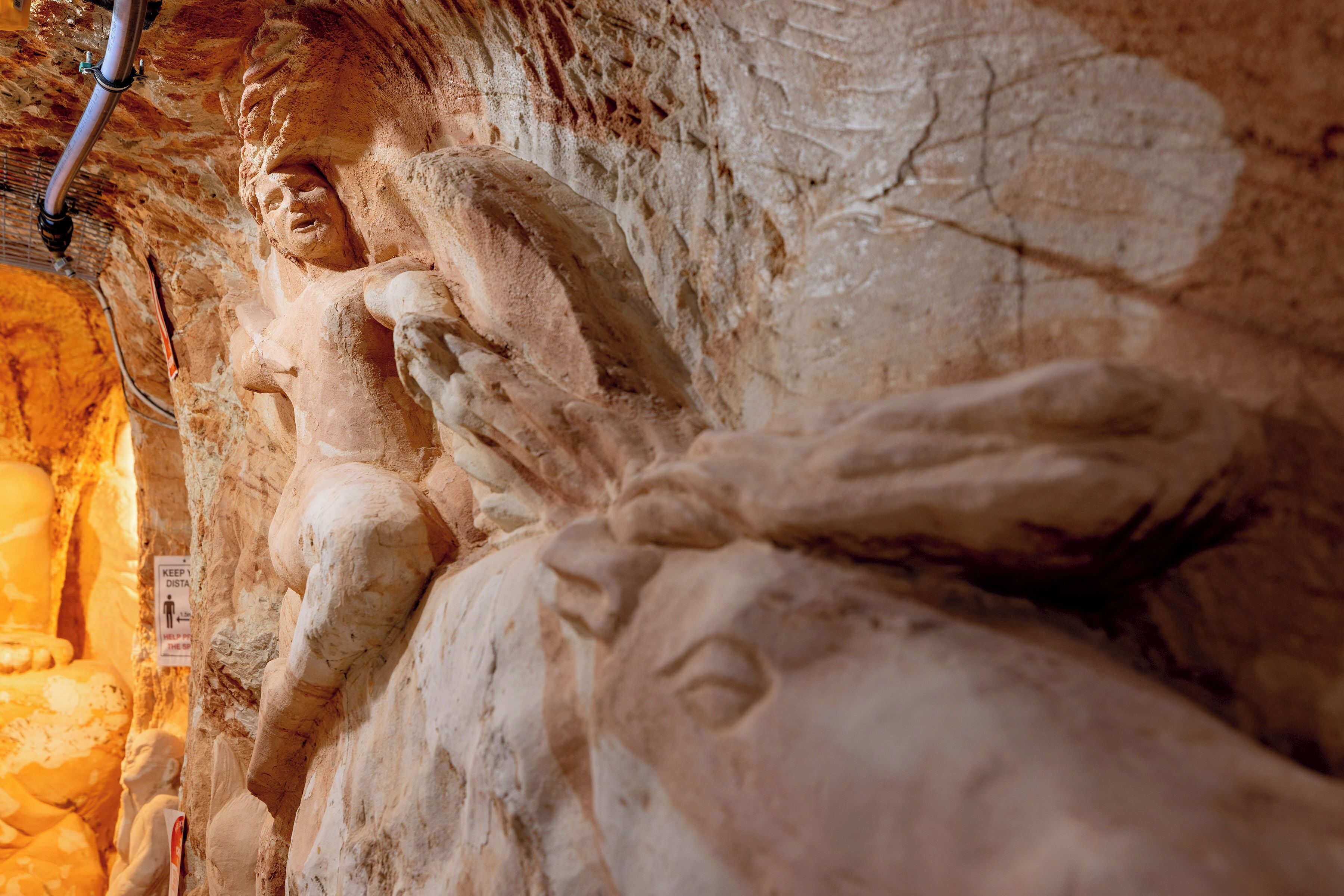 Un detallado grabado en piedra de una figura alada en una pared de cueva.