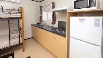 A bunk bed, a sink, a microwave, and a refrigerator in a small kitchen area.