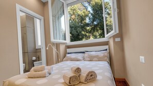Une chambre à coucher avec un lit, des serviettes, une fenêtre et une salle de bain visible.