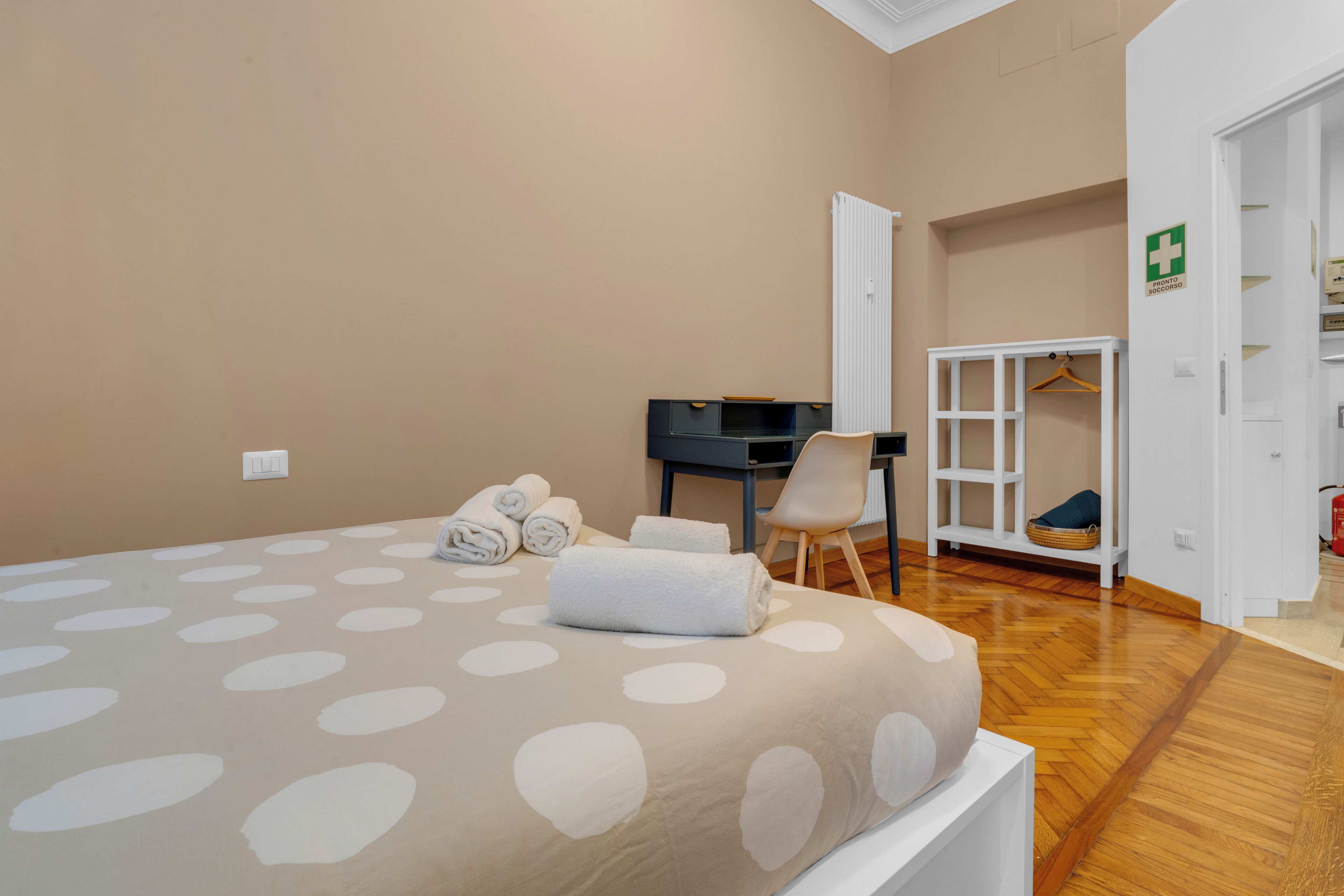A hotel room with a bed, a desk, a chair, and a wardrobe.