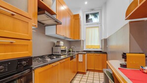 Une cuisine de taille réduite, dotée de meubles en bois, d’une cuisinière à gaz, d’un four à micro-ondes et d’un évier.
