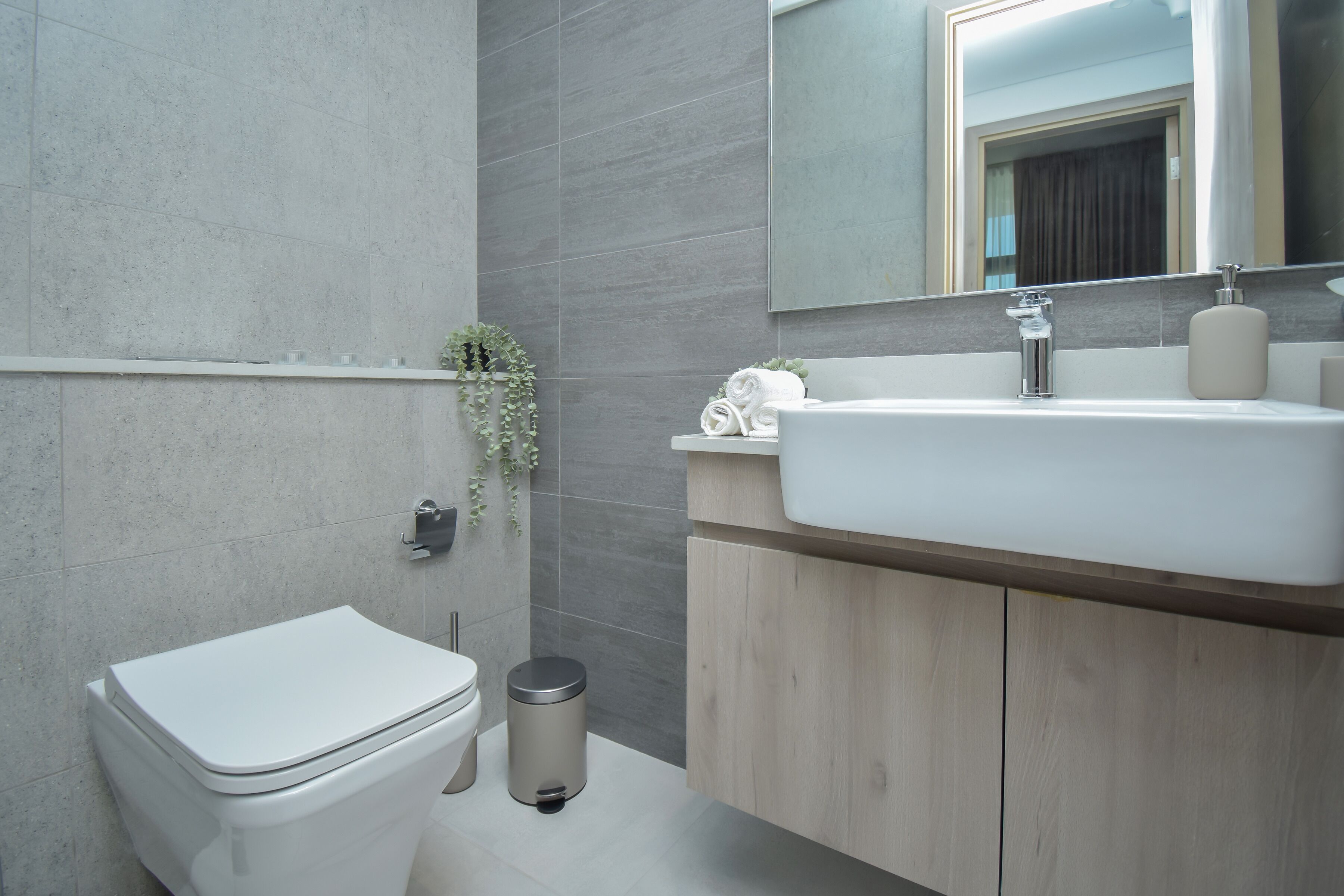 A modern bathroom with a toilet, sink, and mirror.